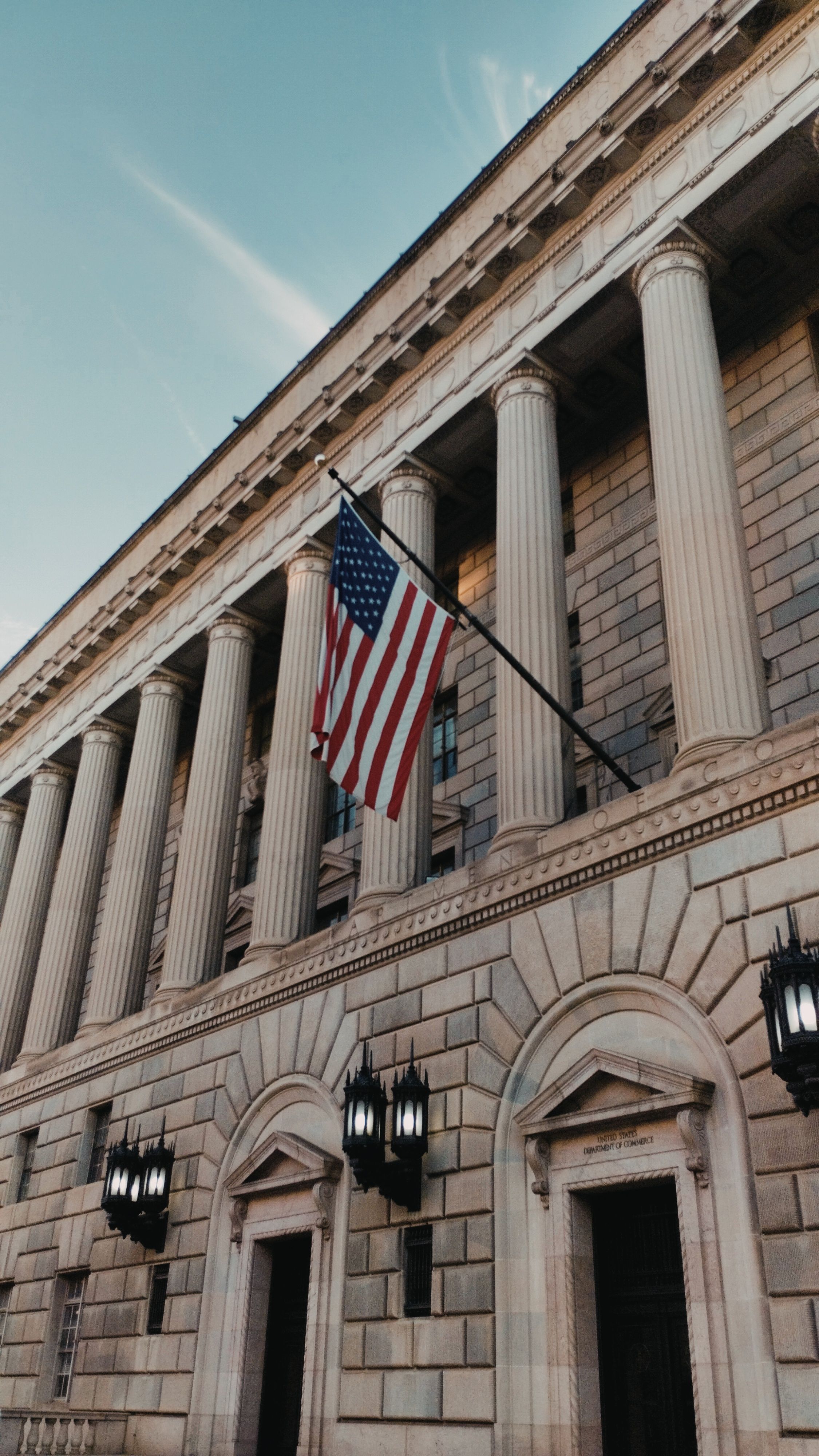 American flag displayed on a neoclassical federal building.